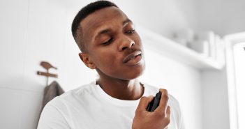 Sollten mehr Männer Parfüm tragen? Mann sprüht sich mit Parfum ein