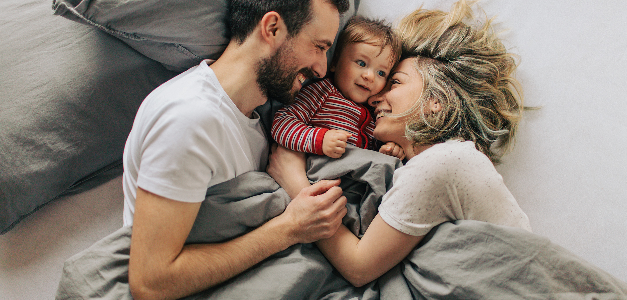 Eltern und Baby liegen glücklich zusammen im Bett