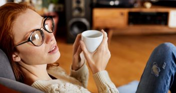 Dein Gehirn liest im Kaffeesatz und liegt oft daneben Frau mit Kaffee in der Hand schaut verträumt