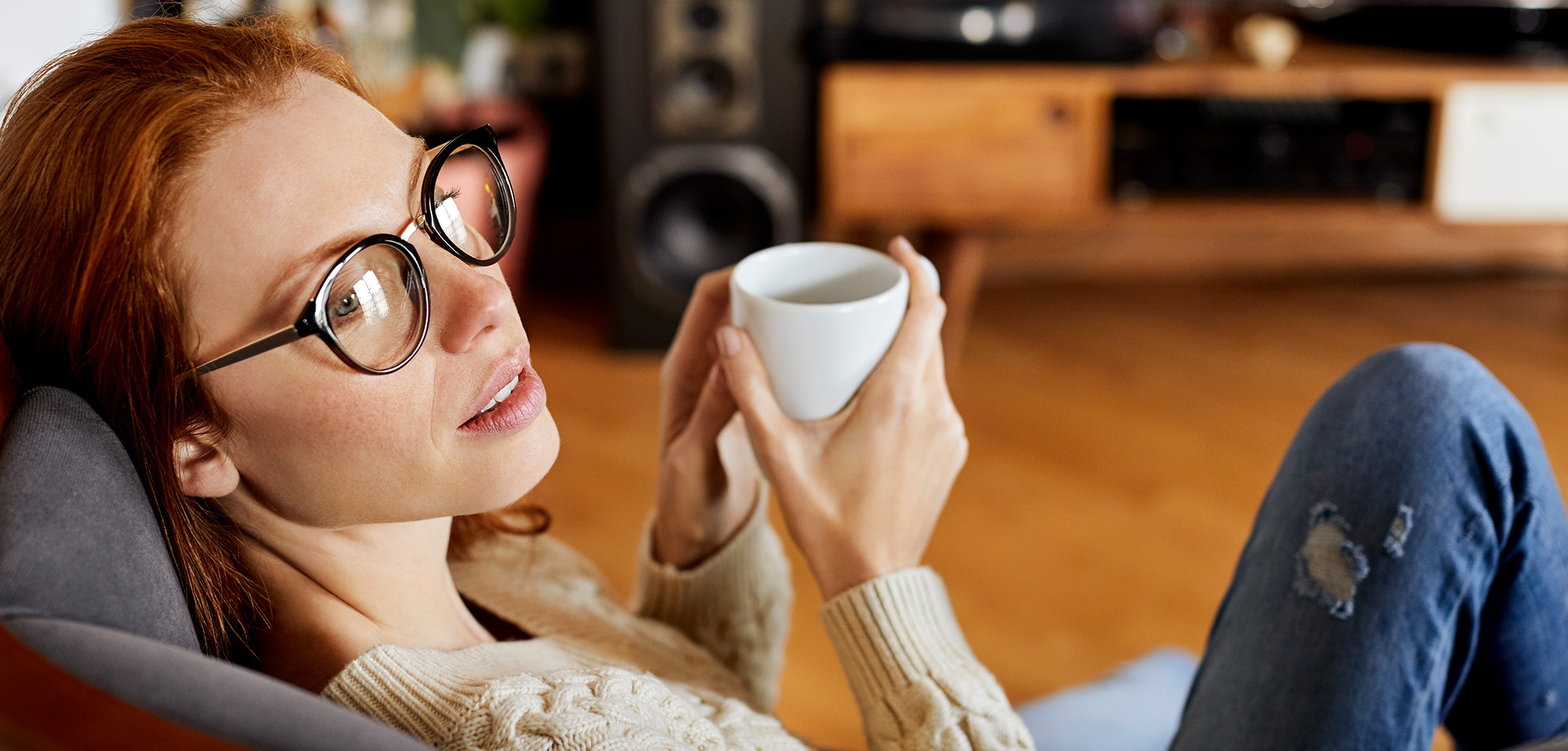 Frau mit Kaffee in der Hand schaut verträumt