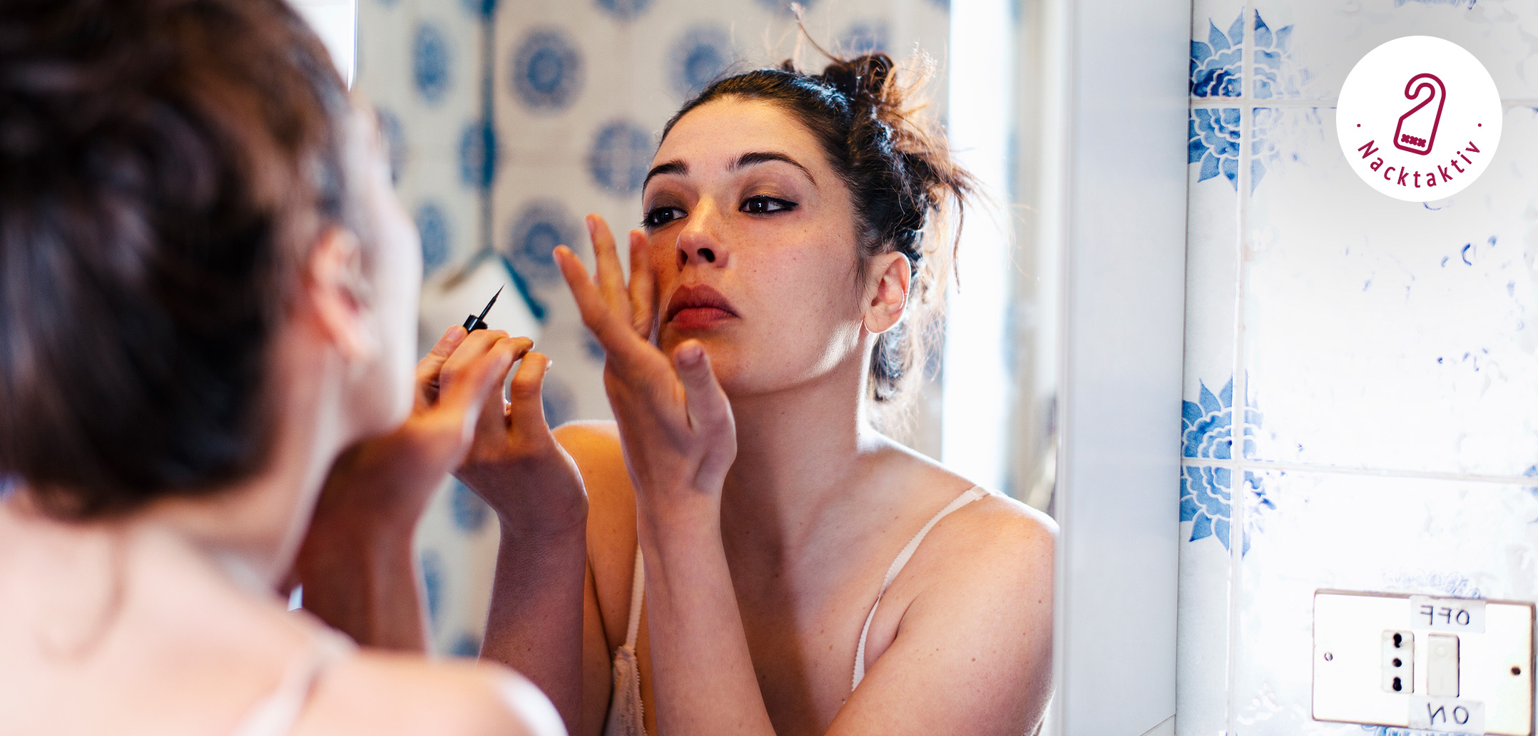 Junge Frau schminkt sich vor dem Spiegel