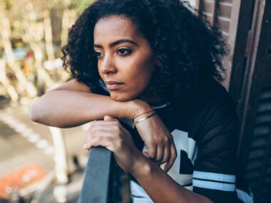 Frau blickt nachdenklich vom Balkon