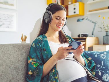 Schwangere Frau hört Podcasts und entspannt